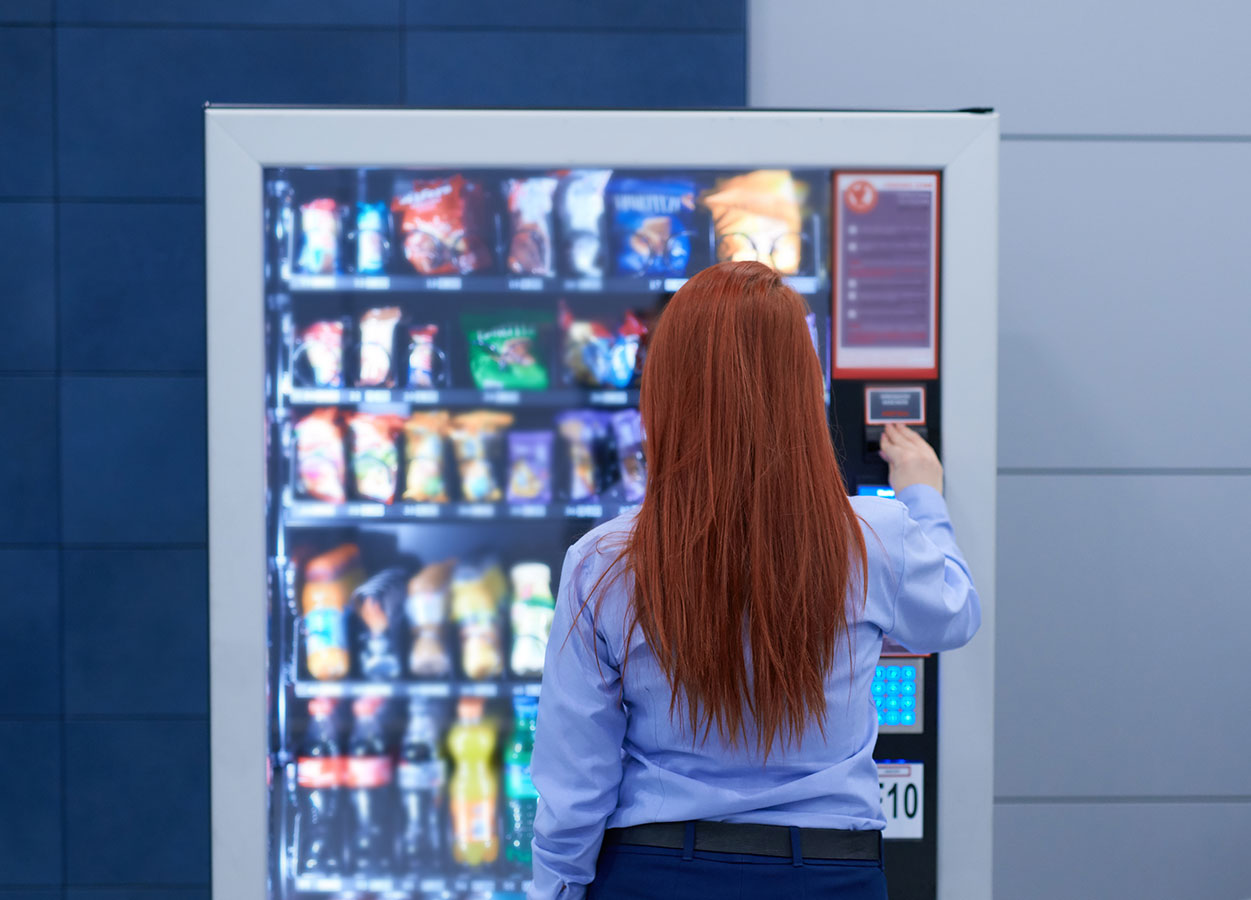 Woman looking to choose which snack to purchase from the vending machine
