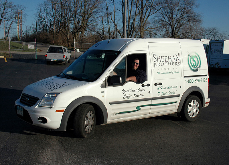 A Sheehan Brothers Vending employee driving a van with the Sheehan logo on the side