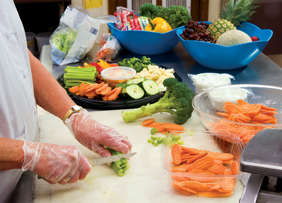A chef preparing a vegetable platter and actively cutting carrots